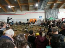 Pohled na tankovou bitvu přes několik řad diváků